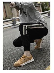 Close-up of brown suede sneakers with thick white rubber soles and black cargo joggers