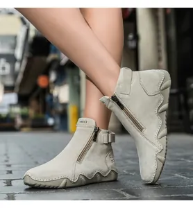 Detail view of khaki leather boots with side zipper, metal buckle, and thick wavy sole