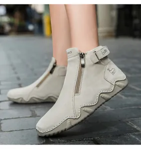 Detail of grey suede leather boots with metallic zipper and decorative buckle strap