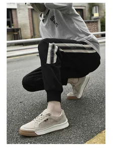Close-up of beige suede leather sneakers paired with striped black joggers on street