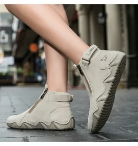 Detailed close-up of beige suede leather ankle boots with side zipper and velcro strap