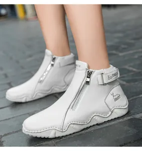 Close-up of white leather ankle boot detailing the metal zipper and DBECI brand logo