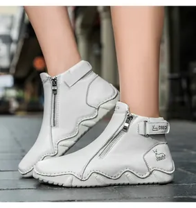 Detail of white leather boots with side zipper, velcro strap and durable wavy sole