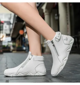 Close-up of white leather boots with litchi texture, side zipper and velcro ankle strap