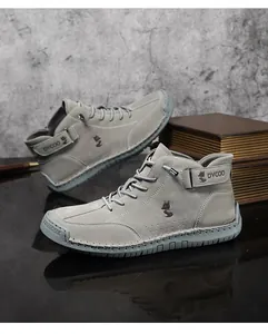 Detail von grauen Wildleder-Boots mit präzisen Nähten und geprägtem Logo an der Seite