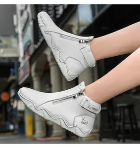 Detail of white leather boots with DBECI logo strap and wavy thick rubber sole