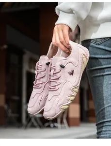 Detail eines rosa Wildleder-Loafers mit weißen Schnürsenkeln und Handnähten