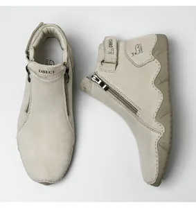 Detail of beige suede high-top boots featuring a side zipper and adjustable buckle strap