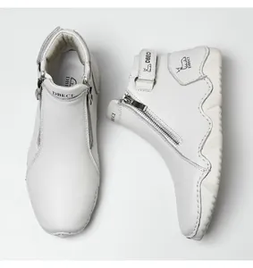 Close-up of white leather boots with grain texture, side zipper and logo strap details