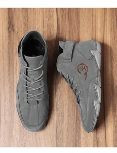Détail de bottines hautes en daim gris foncé avec lacets et bride velcro sur bois