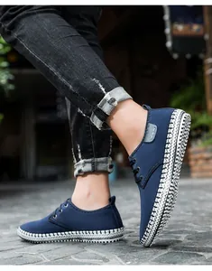 Detail of dark blue canvas sneaker with wavy black and white stitching on outdoor pavement