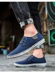 Detail of blue canvas sneakers with braided rope sole trim and white laces shown on feet