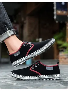 Detail of men's black suede sneakers with red stitching and woven foxing texture