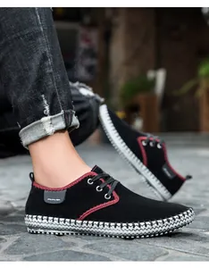 Detail of black casual men shoes featuring red stitching and woven texture sole on stone
