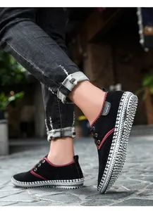 Detail of men's casual black sneakers with red contrast stitching and woven soles