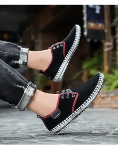 Detail of men's black suede sneakers with red stitching and woven white sole texture
