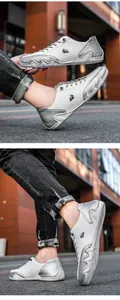 Détail de baskets en cuir blanc et gris avec bout ondulé et logo tête de bélier noir