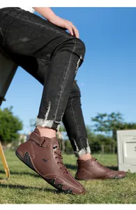 Detail of dark brown leather high-top boots with breathable perforations and rubber soles