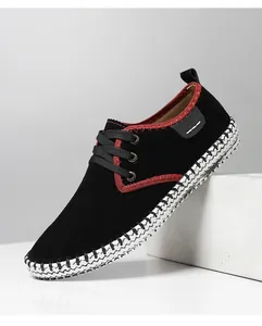 Detailed shot of black suede loafers with red stitching and woven textured sole