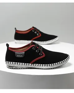 Detail of black suede casual shoes with red piping and woven sole on a platform