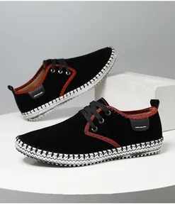 Casual handmade men's sneakers in black suede with red trim and braided sole detail.