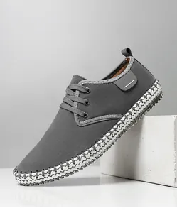 Detail view of grey casual men sneakers with decorative white stitching and matte texture
