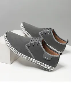 Detail of grey suede casual men's shoes with white woven stitching and lace-up design
