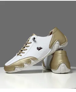 Détail de chaussures décontractées en cuir blanc et doré avec surpiqûres et logo latéral