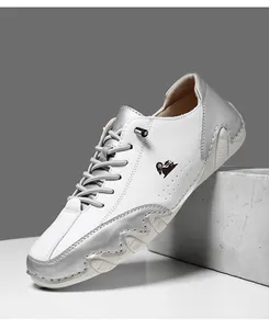 Détail macro des chaussures en cuir blanc et argent avec logo bélier et lacets