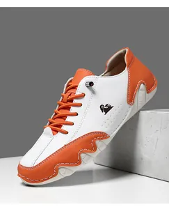 Détail de baskets en cuir litchi blanc et orange avec logo animal latéral et coutures apparentes