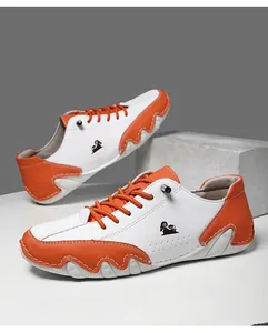 Détail de sneakers en cuir orange et blanc avec semelle ondulée et logo de chèvre