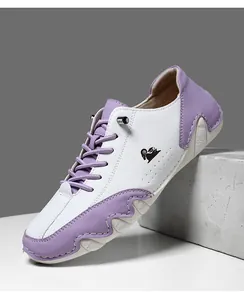 Détail des empiècement en cuir blanc et violet avec logo chèvre sur ces chaussures décontractées