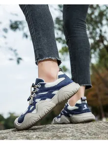 Detail von blauen Wildleder-Outdoorschuhen mit Schnellverschluss auf Waldsteinen