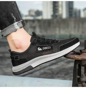 Side view of men's black mesh and suede sneakers with DBECI logo on a street background