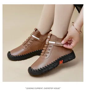Detail shot of brown fashion boots with Velcro strap and orange accent on rubber sole
