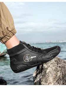 Detalle de botines Chelsea de cuero negro con cuello de punto en rocas