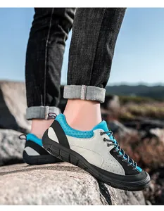 Detail of grey suede hiking shoes with blue mesh on a rocky outdoor mountain trail