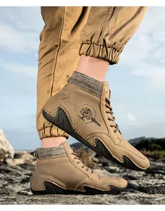 Detalle de botines Chelsea de cuero caqui con cuello de punto y logotipo deportivo