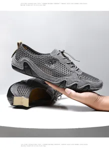Detailopname van grijze mesh herensneakers met golvende rubberen zool in de hand gehouden