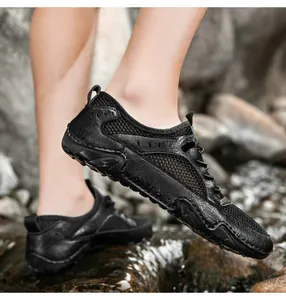 Close-up of black leather and mesh outdoor water shoe on a river rock showing drainage detail