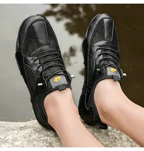 Macro view of men's black leather and breathable mesh outdoor shoe on rocky riverside