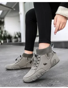Detail von grauen Wildleder-Sock-Sneakern mit Schaf-Logo und gewellter Gummisohle
