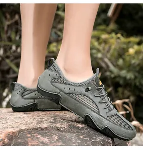 Close-up of men's breathable leather hiking shoes with grey mesh on rocky terrain