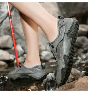 Detail of grey leather hiking shoes with breathable mesh panels on river rocks