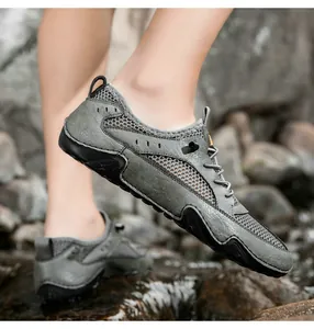 Detail of grey-green hiking shoes featuring breathable mesh on rugged rocky terrain