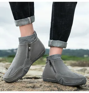 Détail de bottines en cuir gris avec zip latéral et col en tricot sur fond de roche