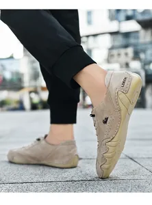 Detailopname van kaki suède herenloafers met LDECK-branding en handgestikte afwerking