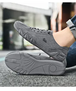 Close-up van grijze suède herenloafers met antislip rubberen zolen en een ram-logo