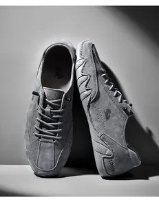 Detailweergave van grijze suède herenschoenen met LDECK-branding en zijdelingse eend