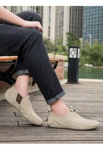 Primer plano de mocasines de ante caqui con suelas de goma y costuras hechas a mano